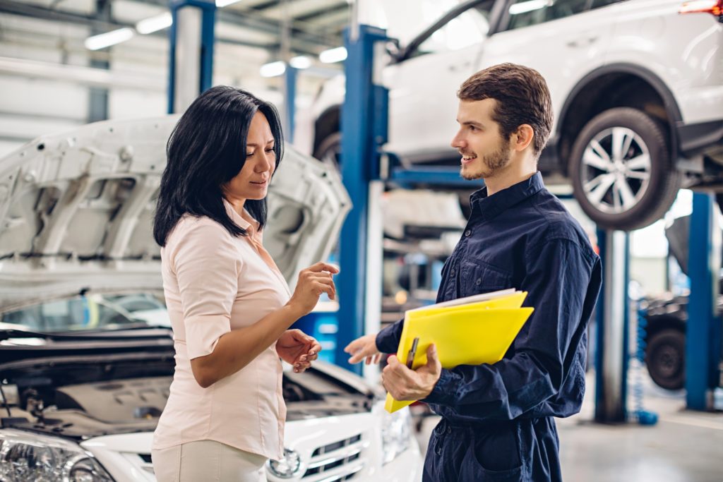 Auto repair marketing: Customer reviewing documents with mechanic at car shop
