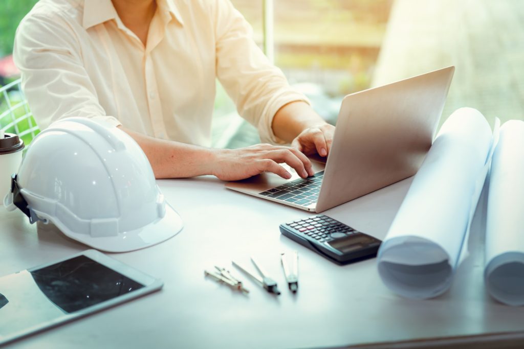 Hard hat, laptop, calculator and other construction business tools