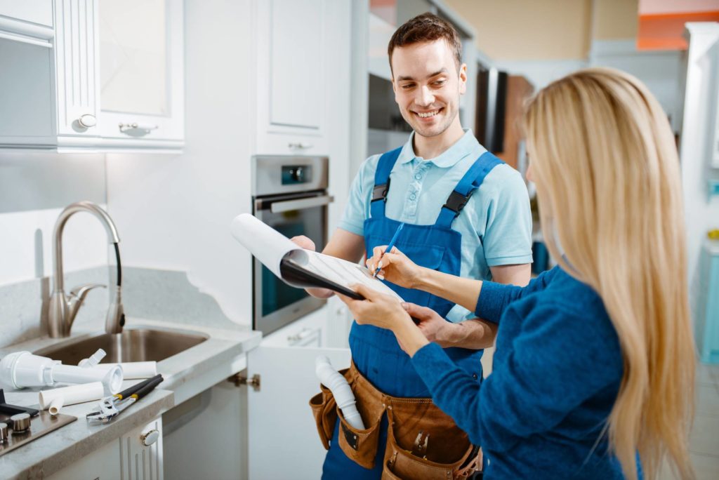 Plumber holding a clipboard reviewing services with a customer