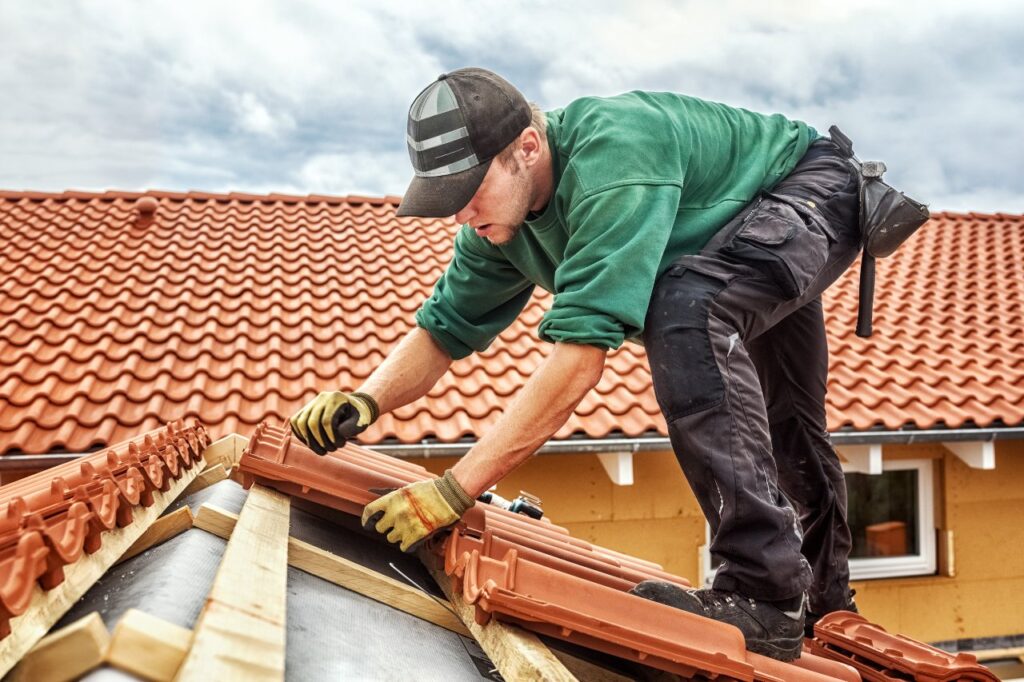 Roofer working on roof with red Spanish tiles