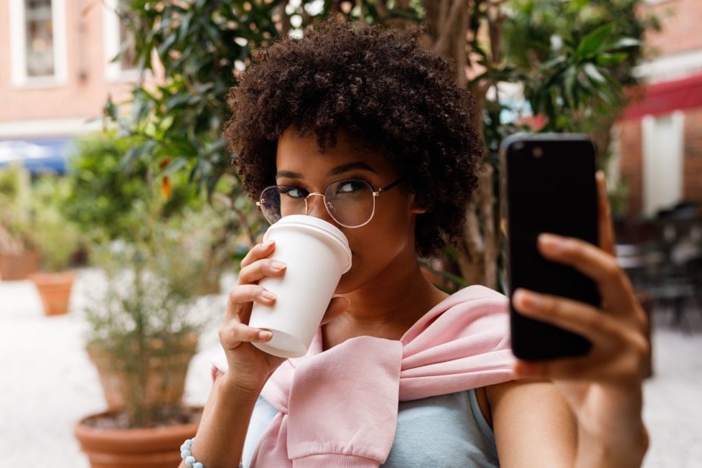 Influencer taking selfie while drinking coffee