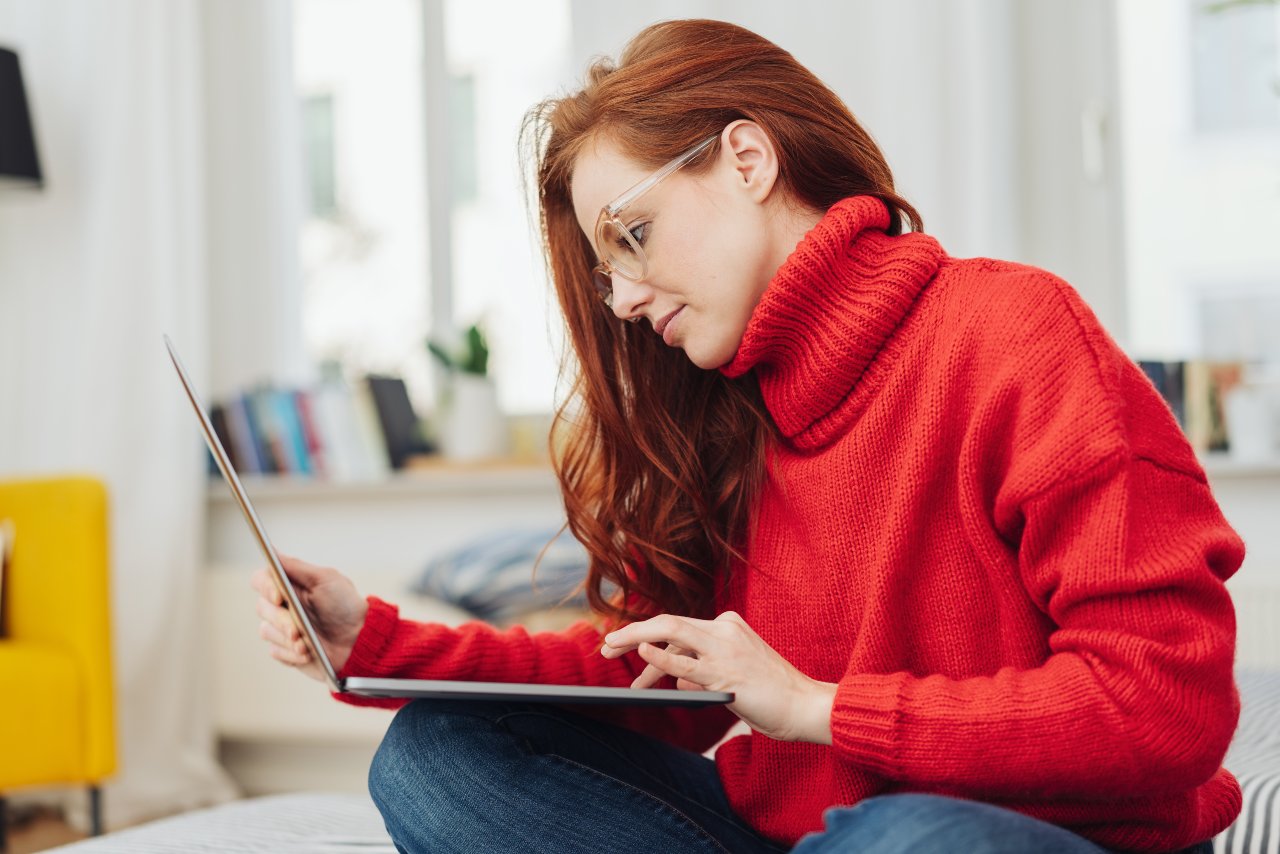 Woman in cozy red sweater working on laptop