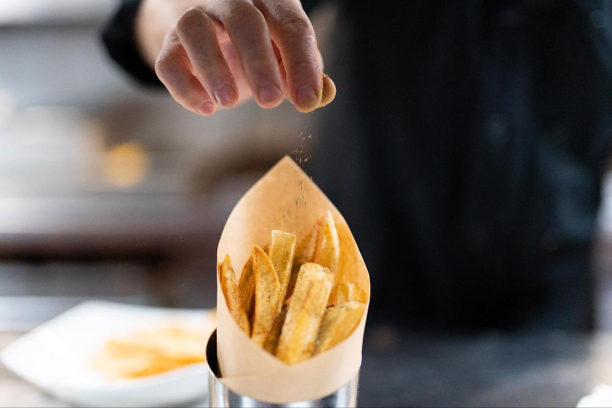 What is a ghost kitchen: chef putting flavored powder on some fries