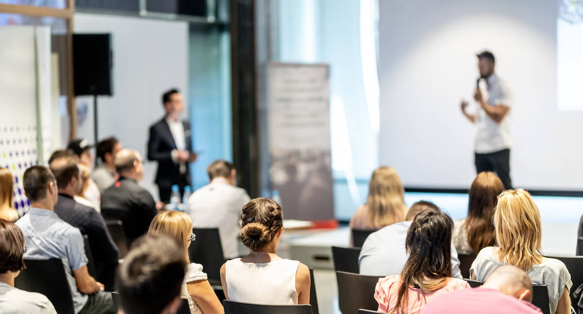 How to write a press release: speaker talking to room full of attendees