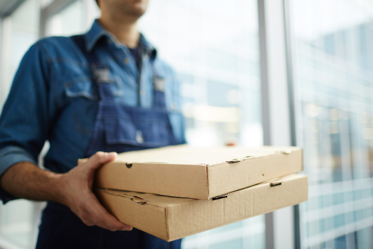 Person carrying 2 boxes of pizza