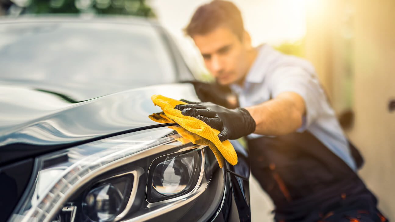 How to start a car detailing business: car detailer wiping the headlight of a car