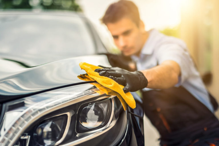 How to start a car detailing business: car detailer wiping the headlight of a car