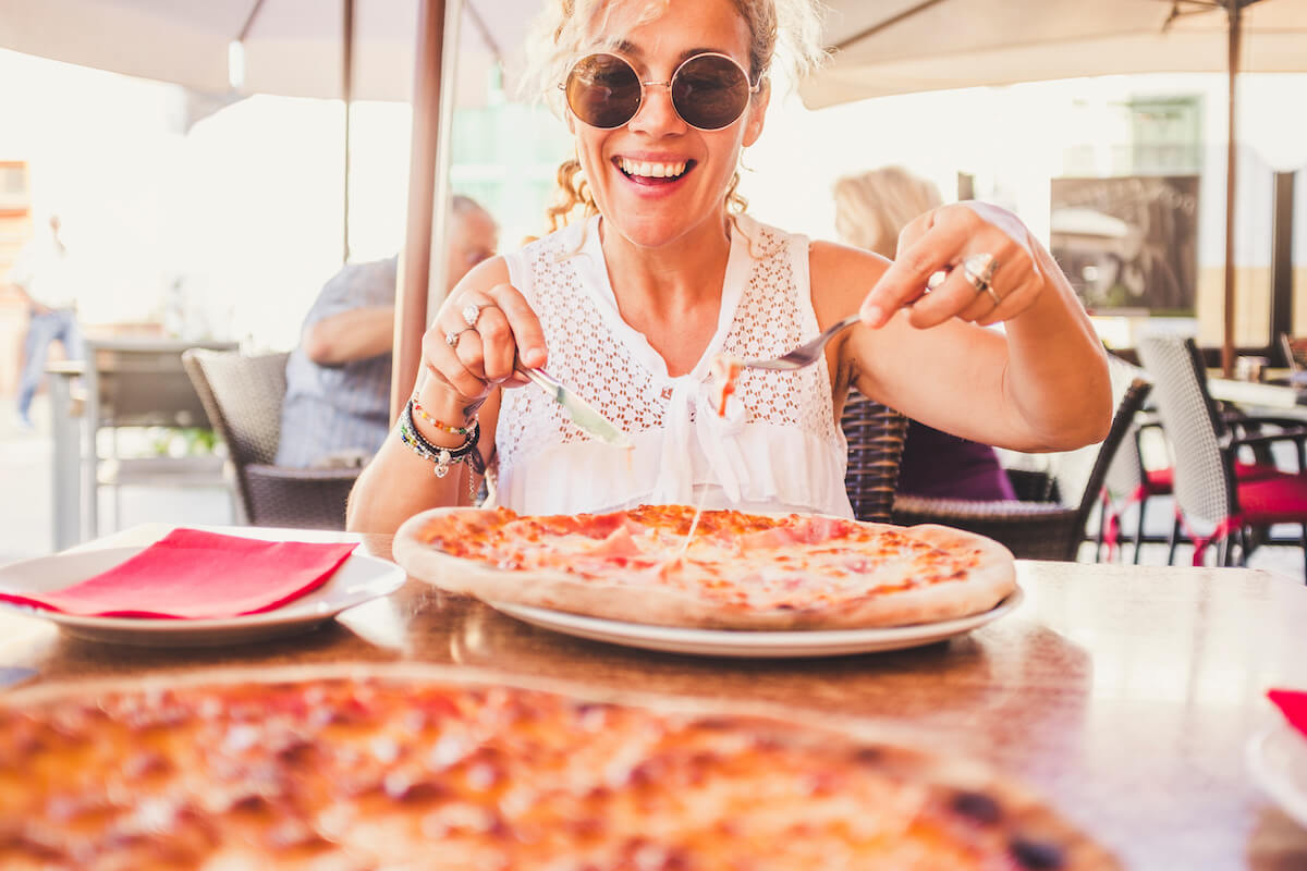 Woman happily eating pizza at a restaurant