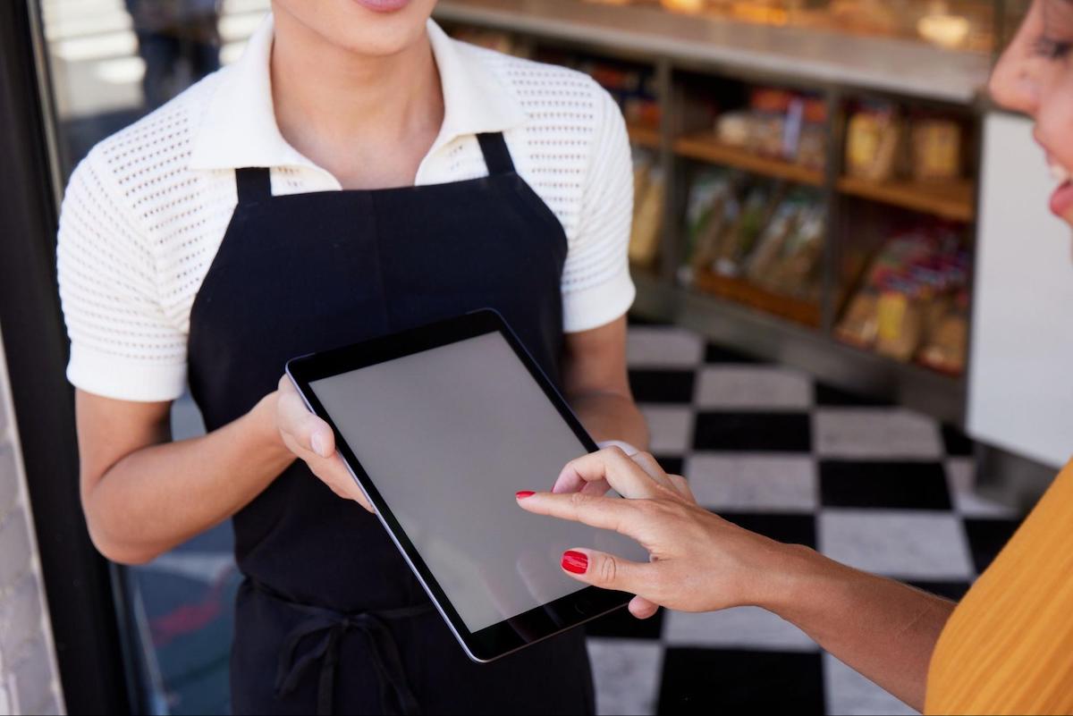 Customer using a tablet while a waiter holds it