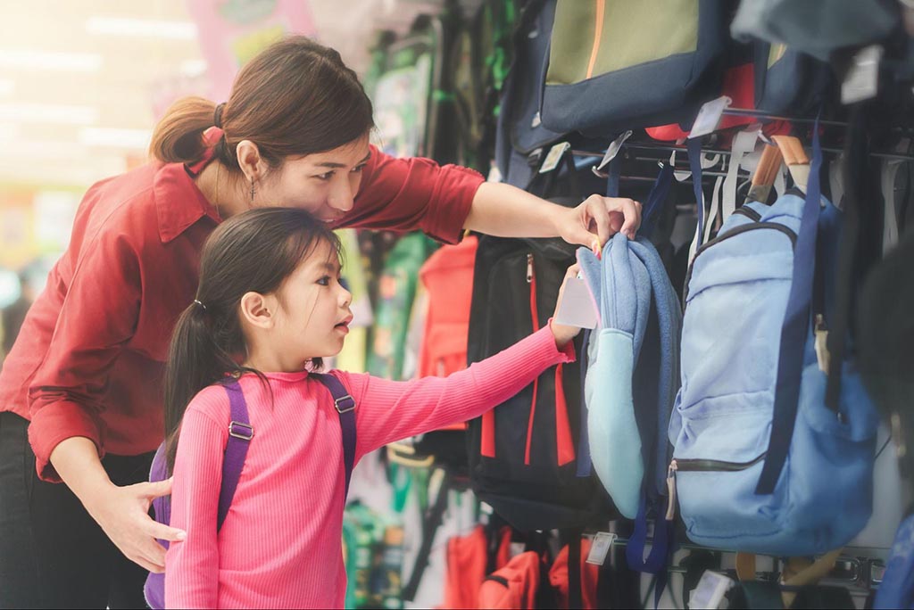 Mother and child looking at backpacks in store