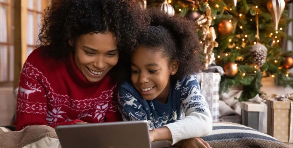 Seasonal marketing ideas: mother and daughter sitting under Christmas tree 