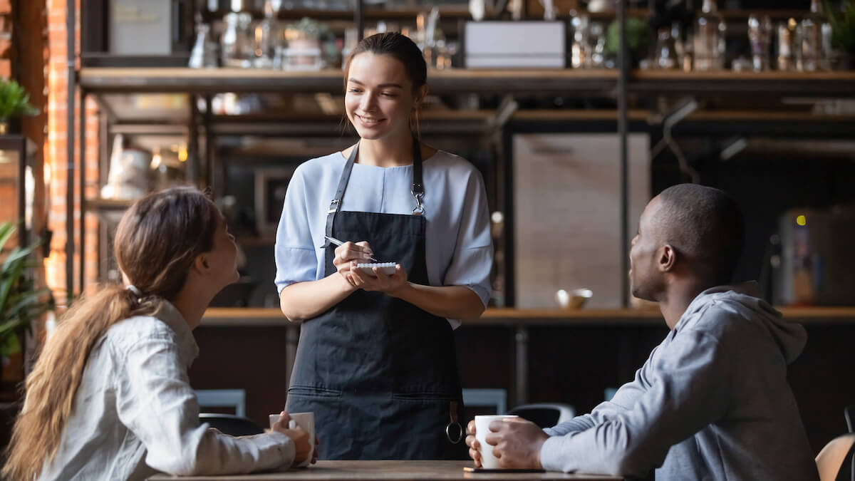 Waiter happily writing down orders from a couple
