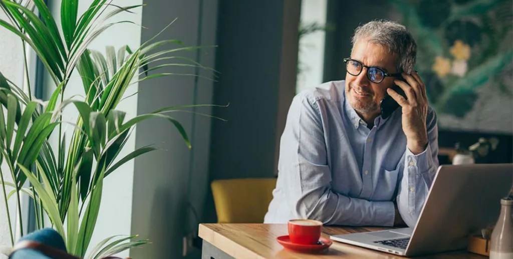 Cold leads: small business owner sitting at desk using his phone