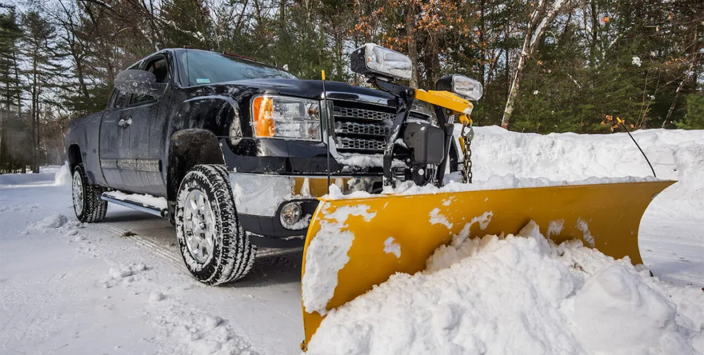 Snow removal leads: pickup truck with a snowplow clearing a road