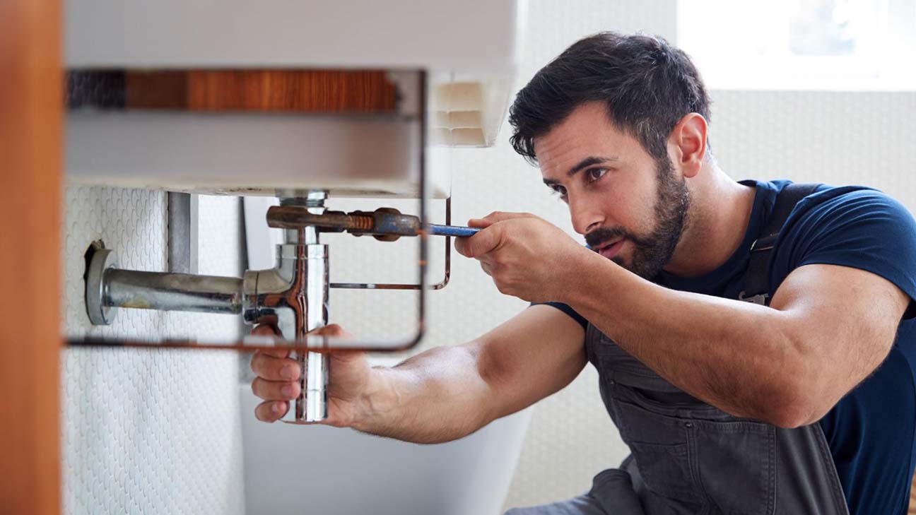 SEO for plumbers: a plumber fixing a leaking sink pipe