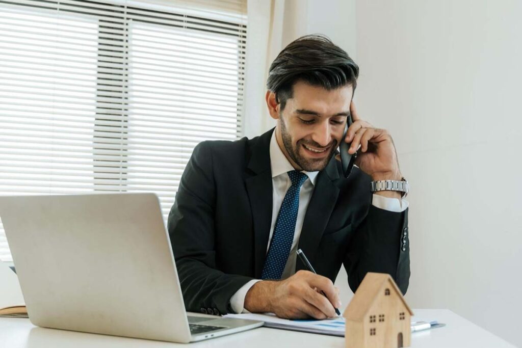 Real estate agent sitting at desk taking a call on his phone