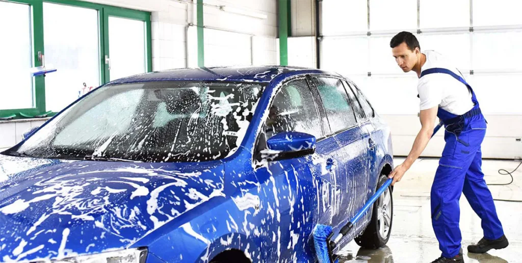 Car wash marketing ideas: car wash owner washing a blue car