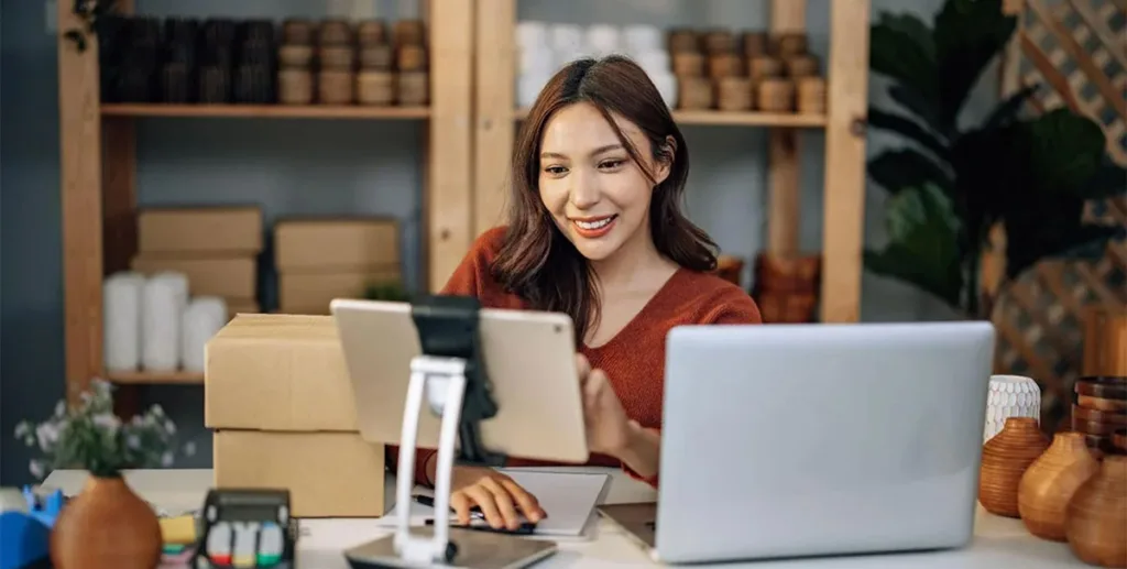 Advertising terms: businesswoman sitting at desk using tablet and laptop