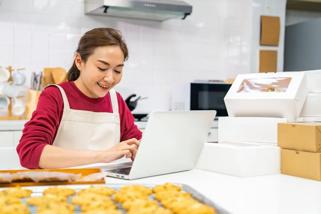 Bakery owner researching paid advertising sites using laptop