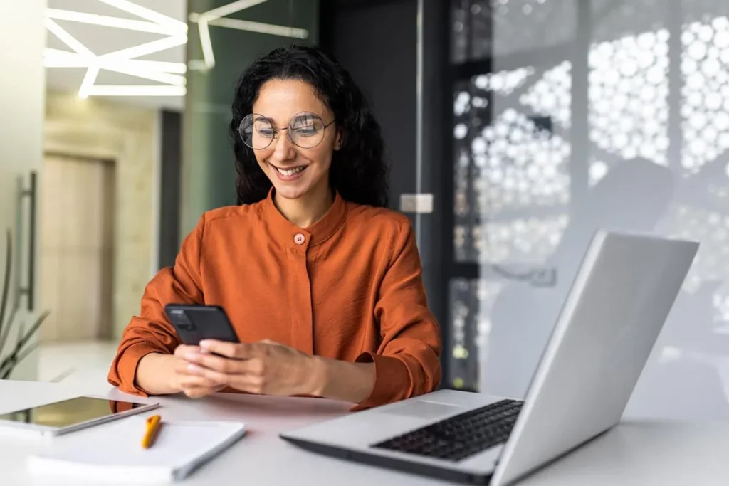 Marketing professional sitting at desk using her phone