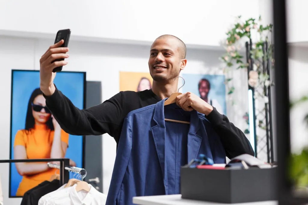 How much does an ad cost: boutique business owner taking a selfie while holding a jacket in his store