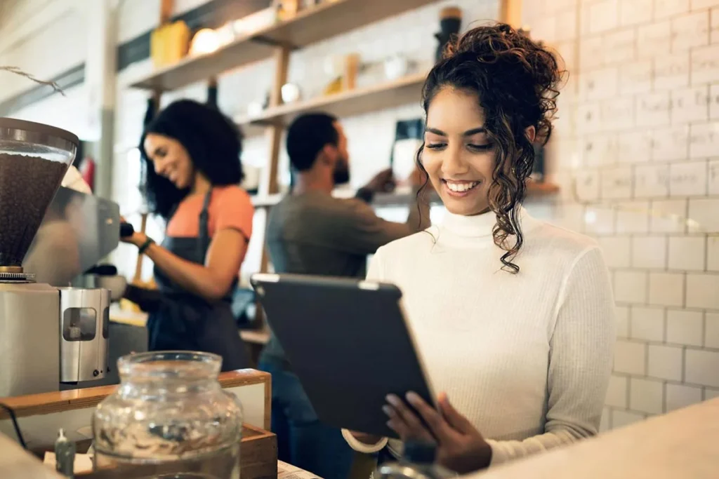 Recruitment and retention: coffee shop owner standing by the counter holding an iPad