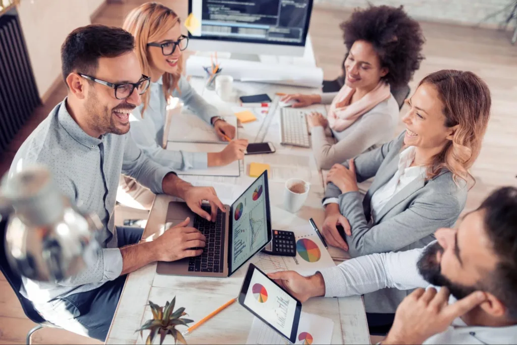 Group of marketing professionals at a table looking at analytics and smiling