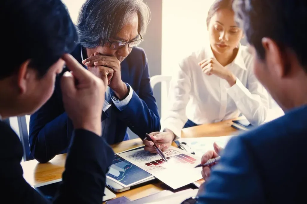 A group of sales professionals gathered around a conference table, analyzing a data report