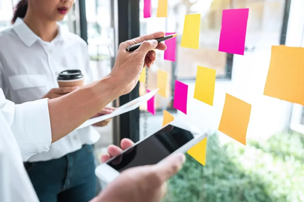 Sales team using sticky-notes on glass wall in office