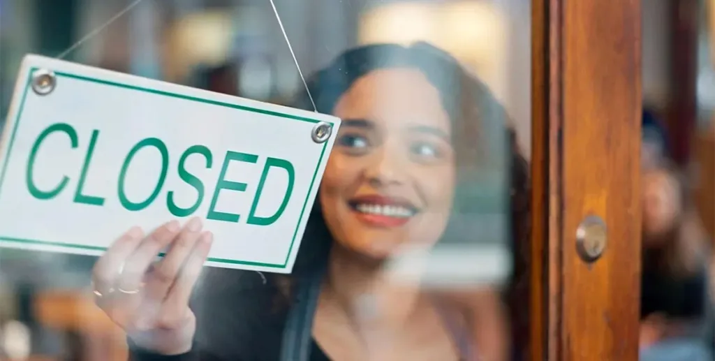 Businesswoman hanging a closed shop sign at window