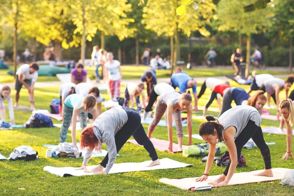 A large group of people doing yoga at a community event in the park