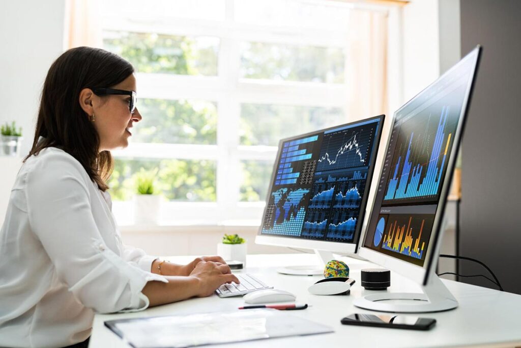 Marketing manager working from home using two computer monitors