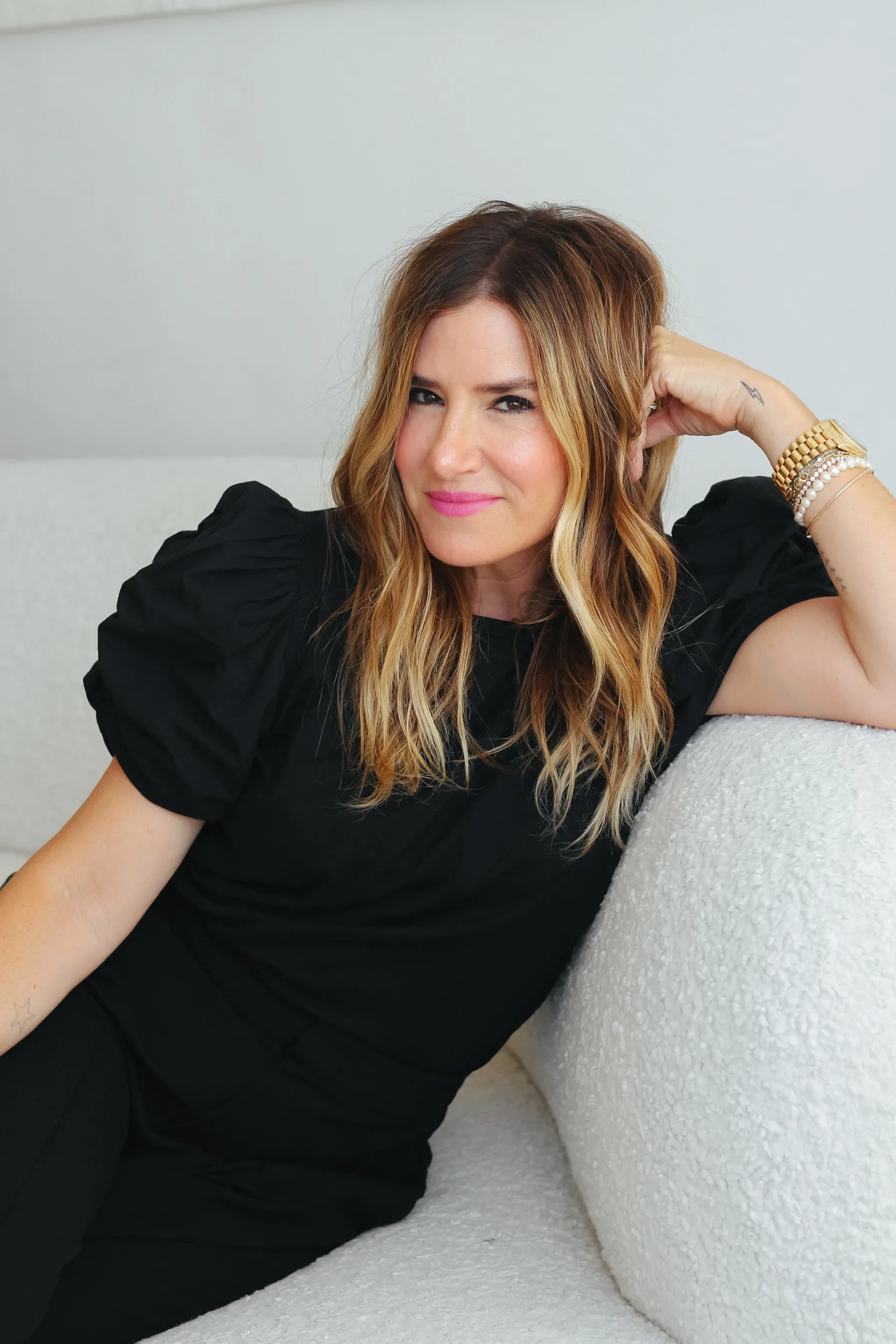 Alli Webb smiling and sitting on a couch