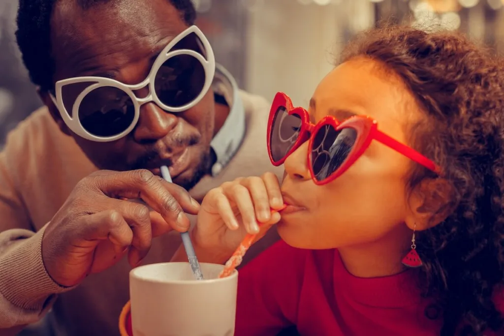 Father’s day restaurant specials: father and daughter sipping a drink from the same cup
