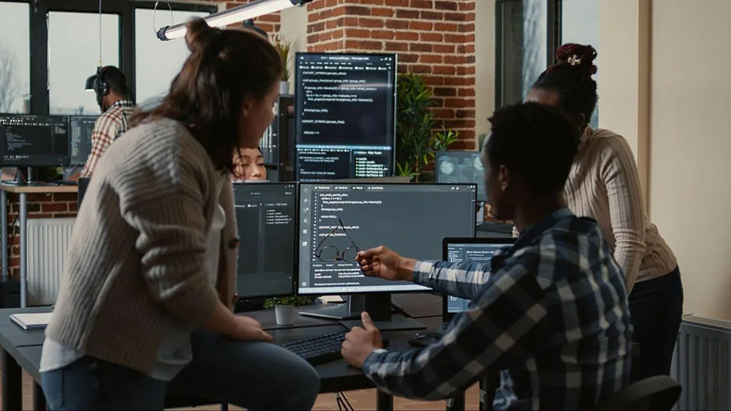 Marketing professionals gathered around a laptop in office