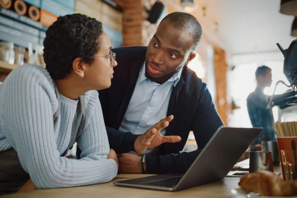 Coffee shop owner discussing online forums with an employee behind the counter