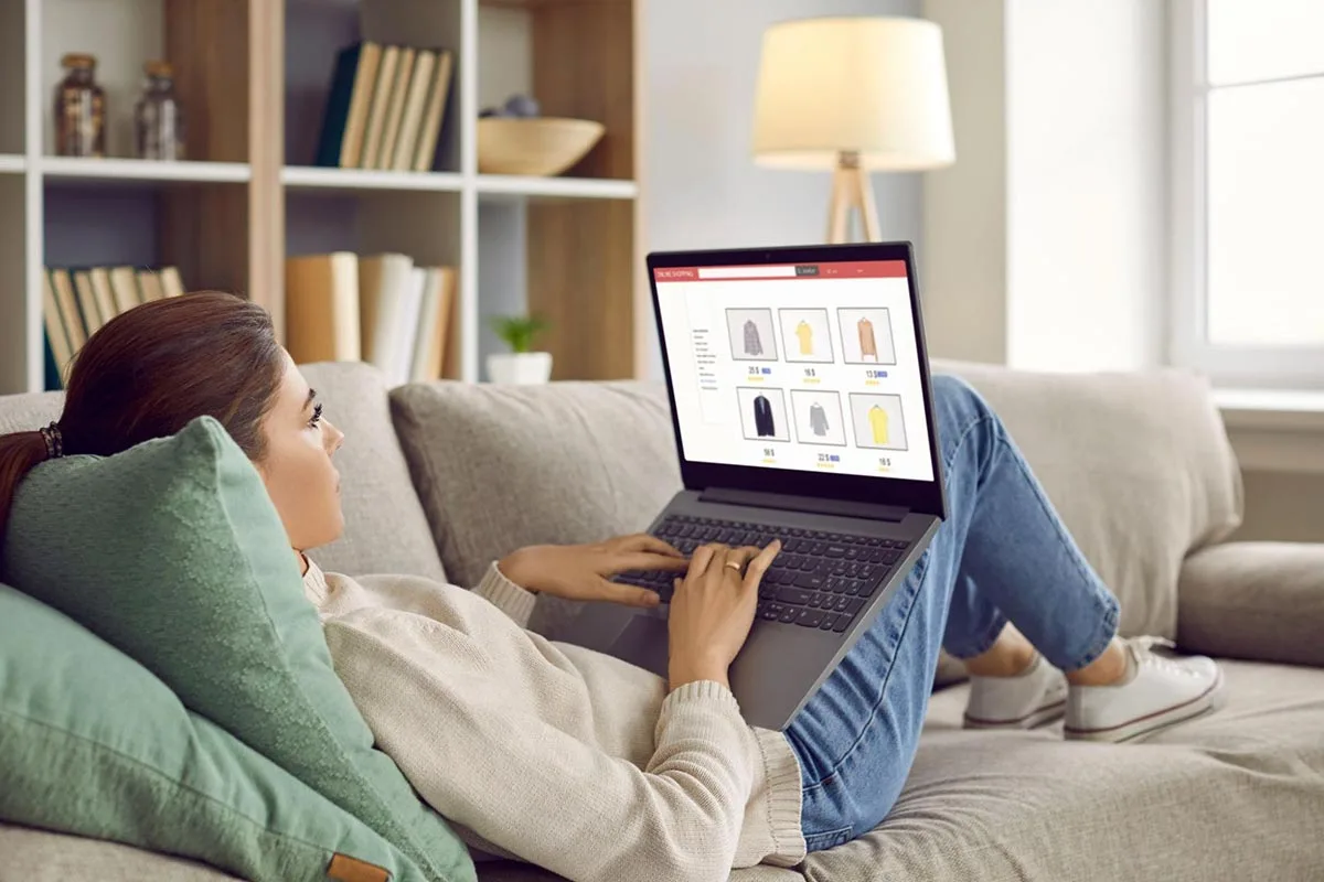 Young woman sitting on sofa doing online shopping using her laptop