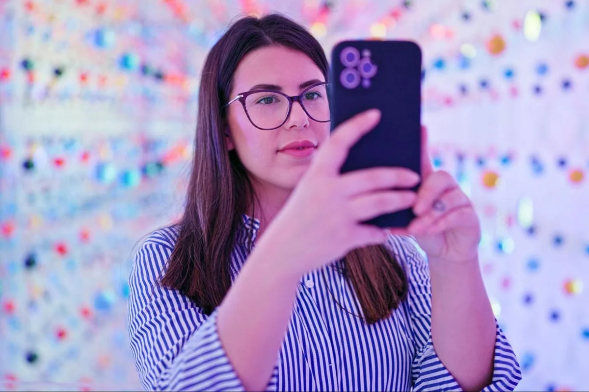 A young woman wearing glasses taking a selfie with her phone