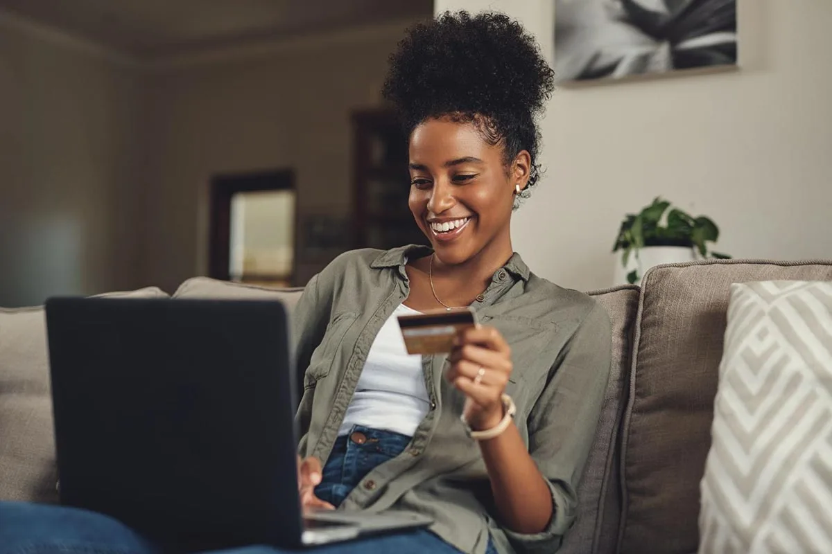 Young woman sitting on a sofa using her phone for card payment