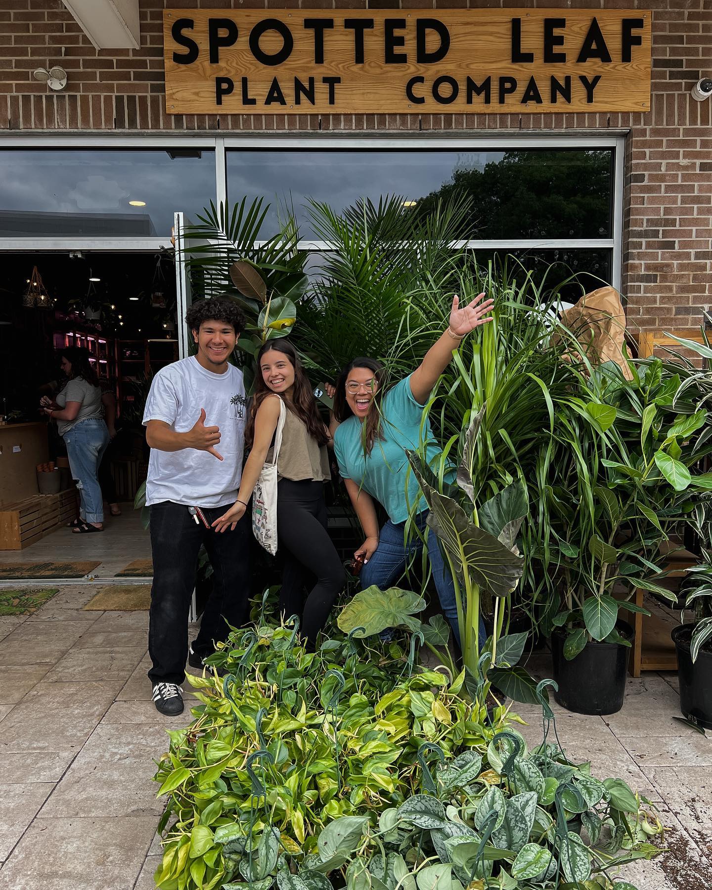 Spotted Leaf employees surrounded by plants smiling and posing in front of the store