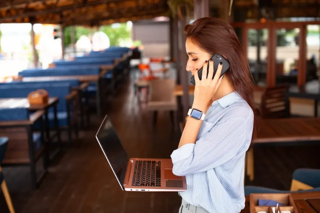Restaurant labor cost percentage: restaurant manager talking on the phone while carrying her laptop