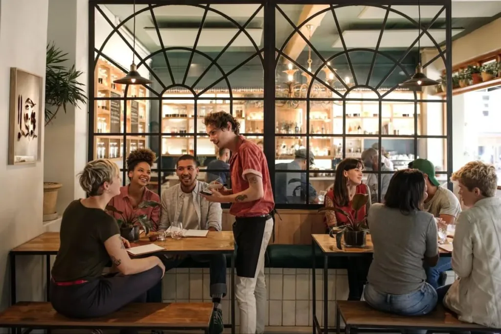 A restaurant server is taking an order from customers seated at a table.