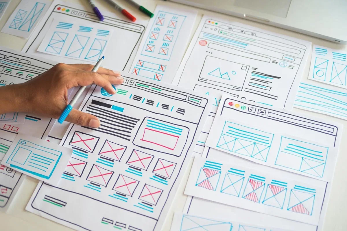 Web wireframes laid out on a table showcasing the layout and design structure for a website