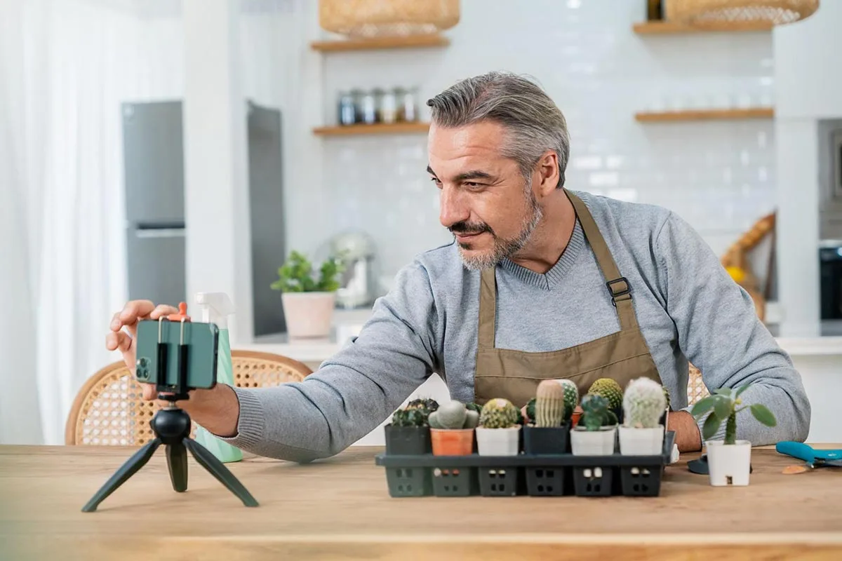 Business owner recording a social media video to promote his local business with smartphone and tripod in a shop setting