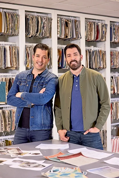 Drew and Jonathan Scott smiling in front of material samples