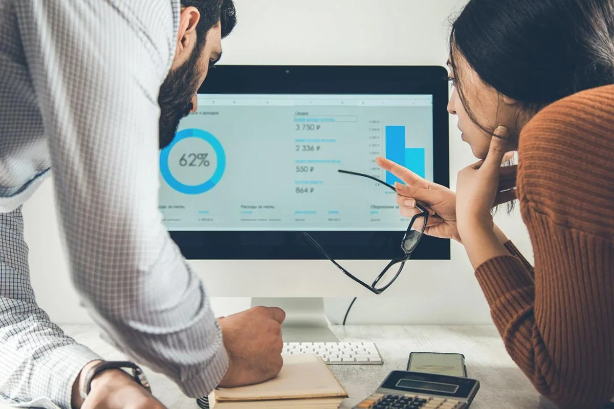 Two CPG professionals analyzing data on a laptop, focusing on charts and graphs to gain insights