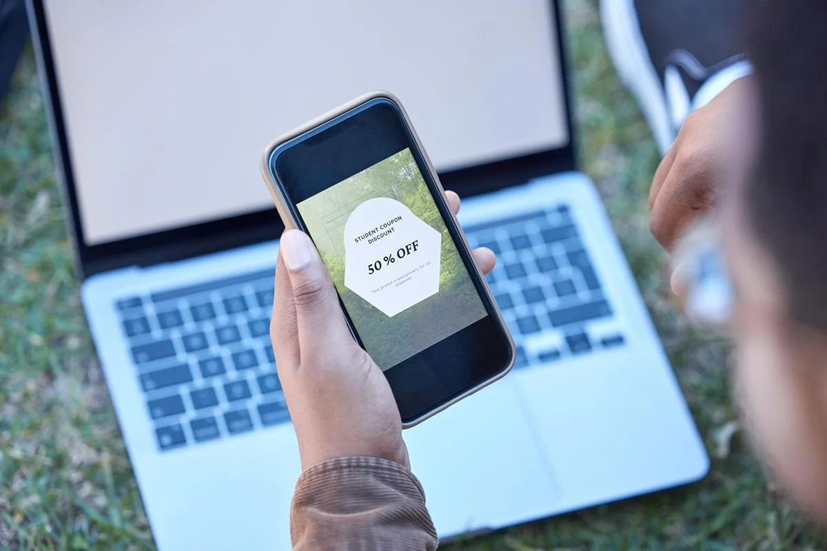 A man holding a phone and looking at a sale offer displayed on the screen