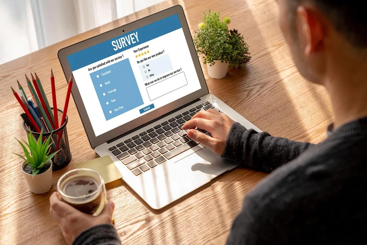 A small business owner creating a customer online survey on their laptop, focused on gathering insights into how their brand is perceived