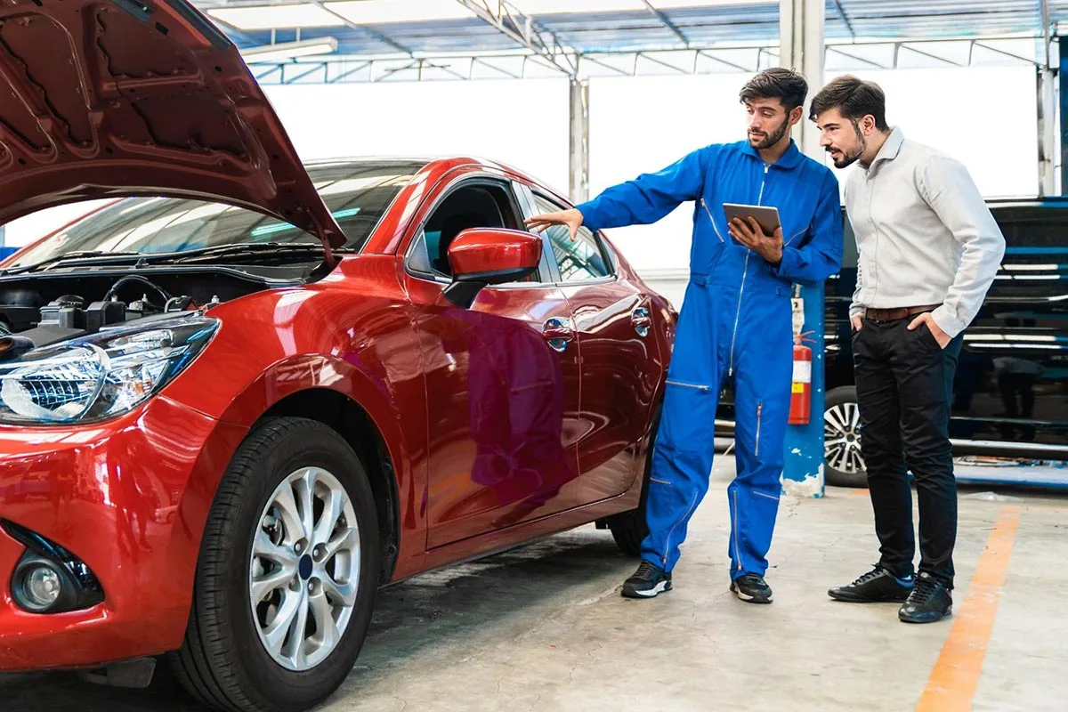 A car dealership business owner talking to a customer in a showroom setting.