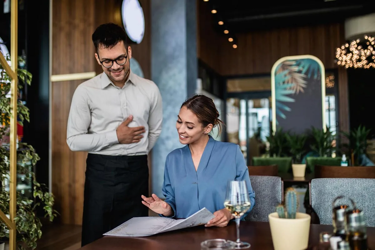 A woman ordering her meal from a server at a restaurant table.
